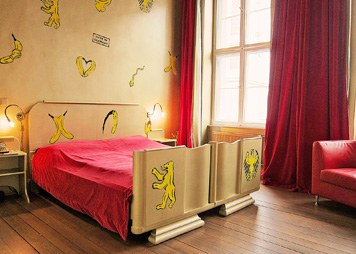 das Zimmer 102 mit einem goldenen Bett und roten Samtvorhänge