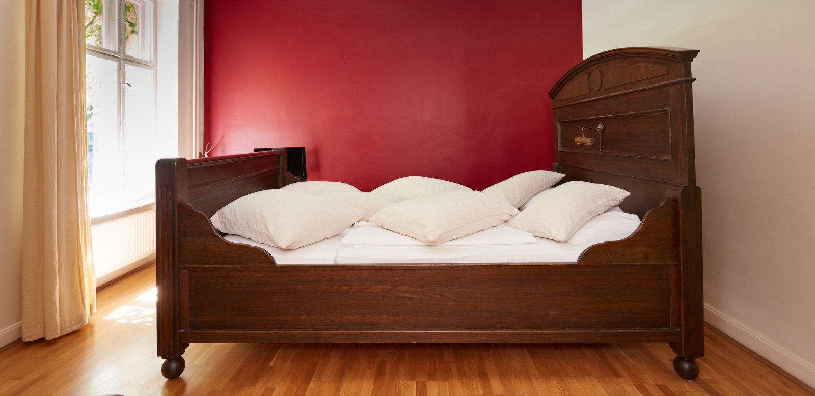 Helles Doppelzimmer mit roter Wand und großem Bett
