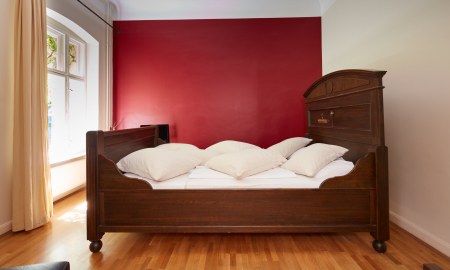 Helles Doppelzimmer mit roter Wand und großem Bett