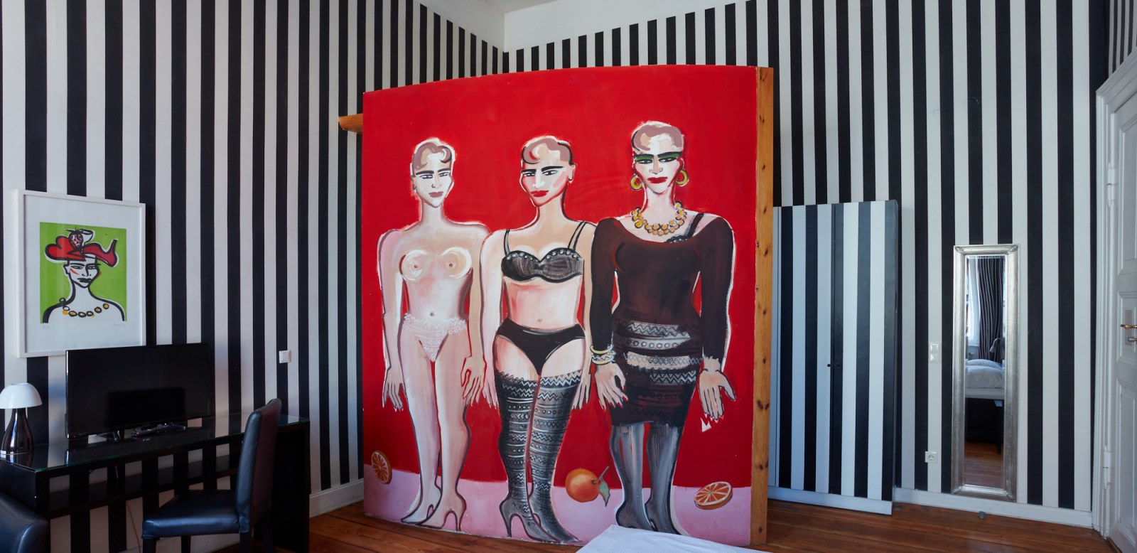 Ein cooles Hotelzimmer in schwarz-weiß gestreift und mit drei gemalten Frauen an der Wand.