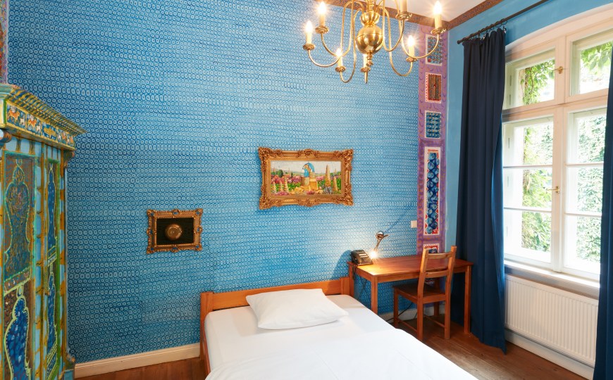 Ein Hotelzimmer in blau und mit Kronleuchter